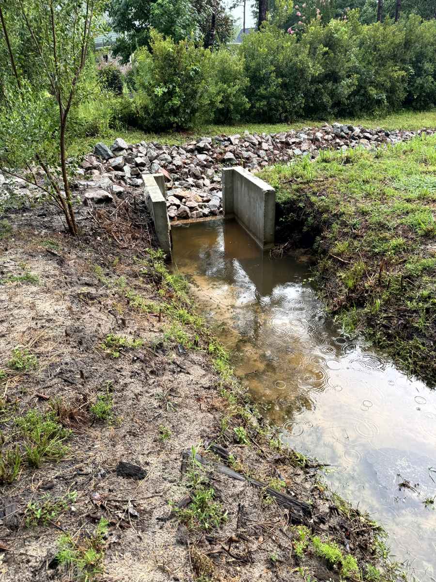Concrete flared outlet with riprap carrying muddy stormwater during rain